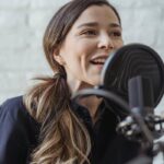 Happy woman talking while recording podcast in studio